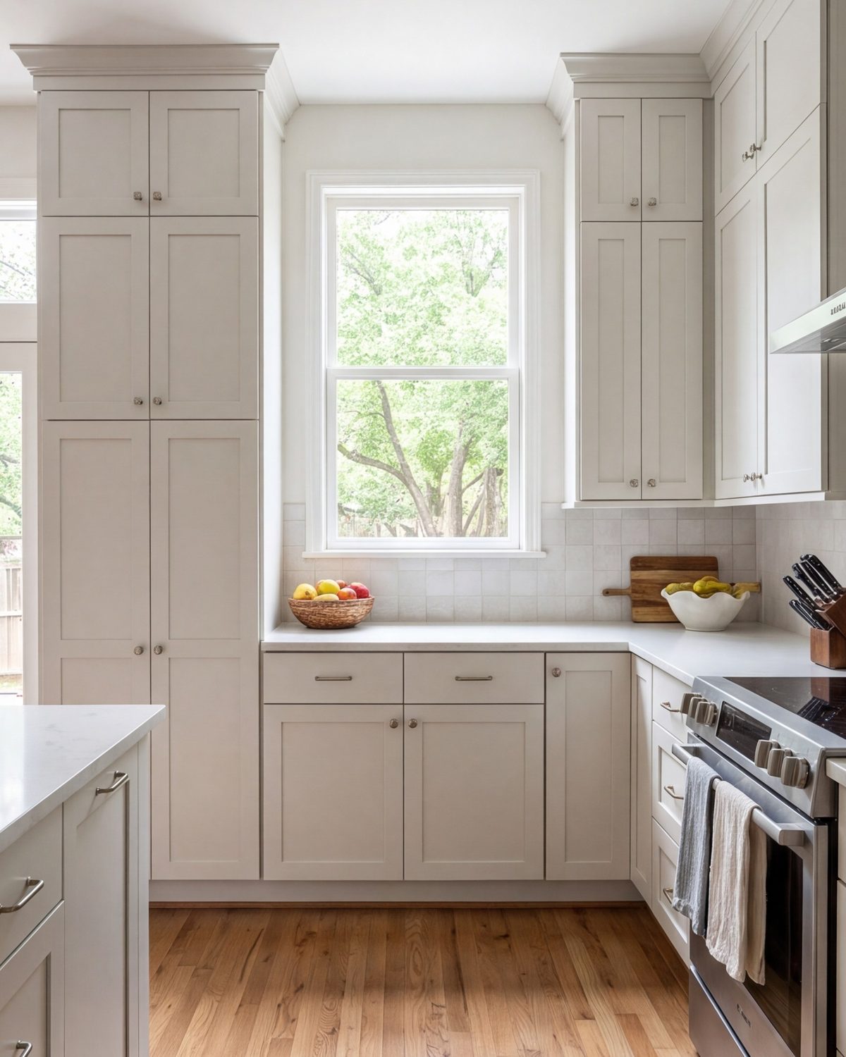 Bright kitchen corner with full-height cabinets and a window, tall view